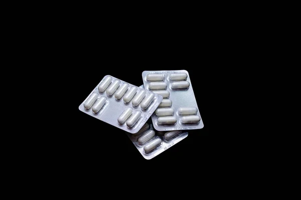 White pills in silver packs on a black background, isolate, copy space — Stock Photo, Image