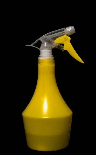 Closeup yellow spray bottle in full growth, isolated black background — Stock Photo, Image