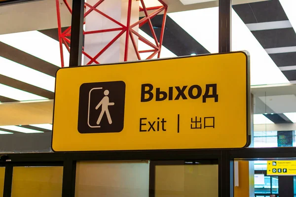 Yellow sign with a black inscription exit in different languages at the airport