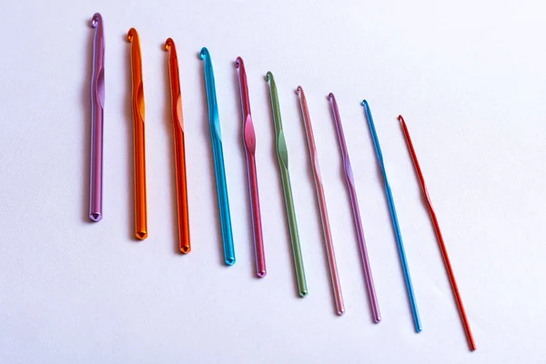 Crochet hooks of different sizes and colors arranged in one row, rainbow palette — Stock Photo, Image