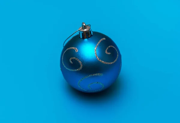 Christmas blue toy with silver spirals for decoration on a turquoise background — Stock Photo, Image