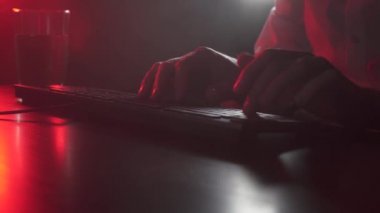 Bir adam bilgisayarda çalışıyor ve su içiyor.