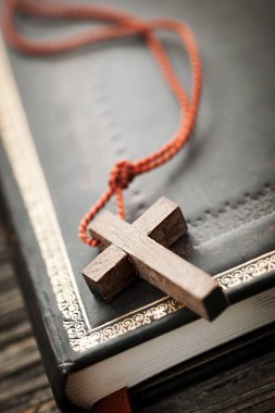 Closeup of wooden Christian cross necklace next to holy Bible clipart