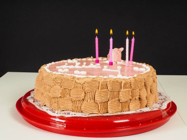 Gül ve çikolata desenli pembe badem ezmesi kaplı bir doğum günü pastasında lig mumları.