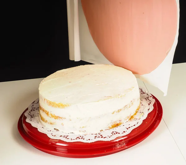 人们在红色塑料托盘上的图层蛋糕上加一个粉红色的杏仁盖层 — 图库照片
