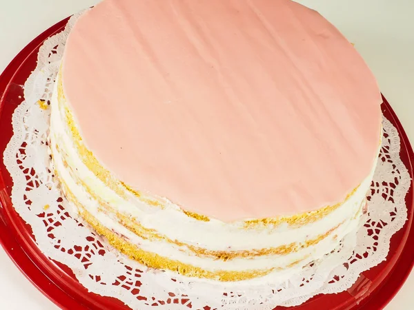 红色塑料托盘上的一层蛋糕上的粉红杏仁盖层的闭合 — 图库照片
