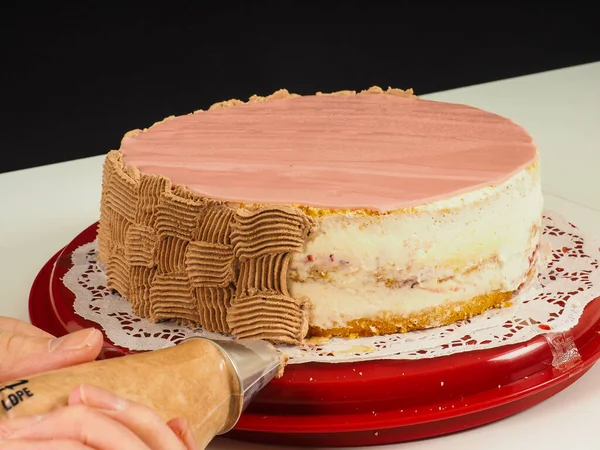ベイカーはピンクのマジパンカバー層ケーキにチョコレートパターンを作成します — ストック写真