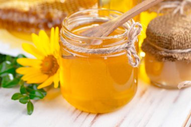 Bee honey in a jar with a flower, on the old background. clipart