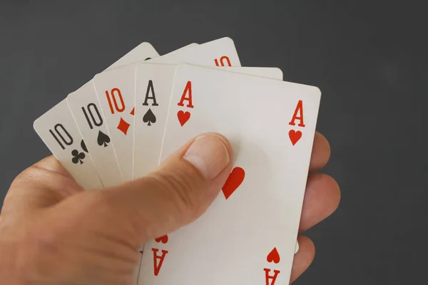 Poker hand with three cards of ten and two aces - close up on black background