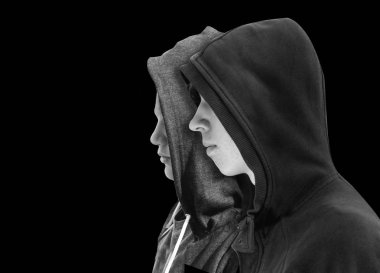 İki genç çocuklar birbirine yakın siyah hoodie ayakta siyah arka plan üzerine izole profil ile sorunlu. Siyah beyaz resim.