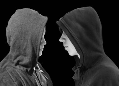 İki genç çocuklar siyah hoodie ayakta birbirimizi önünde siyah arka plan üzerine izole profil ile sorunlu. Siyah beyaz resim.