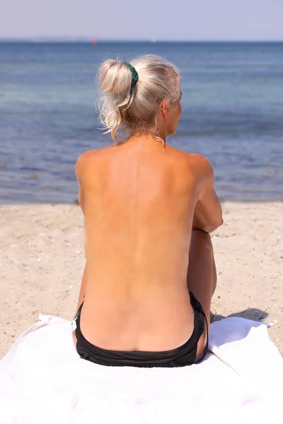 Mooie Blonde Zon Gebruinde Topless Vrouw Zittend Strand Zon Kijkt — Stockfoto