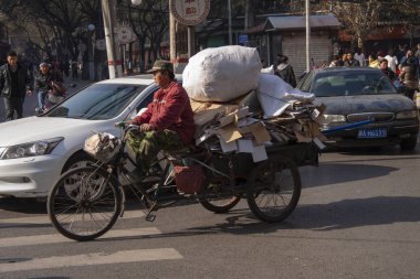 Pekin, Çin için bir sokakta mal olan Çinli bir kargo üç tekerlekli bisiklet sürme dolu. Çin'deki popüler nakliye kargo bisiklet veya navlun bisikletler yapılmaktadır. Beijing, Çin - 29 Aralık 2014