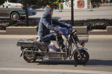 Çinli bir yol Çin'deki motosiklet sürme. Popüler nakliye Çin mopedler yapılmaktadır. Beijing, Çin - 29 Aralık 2014