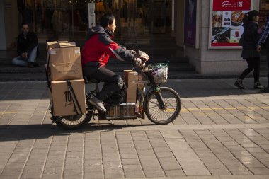 Çinli bir kargo sürme motosiklet yüklü karton Çin bir sokakta sarılı mal ile. Çin'deki popüler nakliye kargo bisiklet veya navlun mopedler yapılmaktadır. Beijing, Çin - 29 Aralık 2014