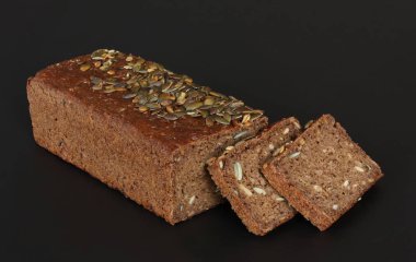 Ev çavdar ekmeği ayçiçeği tohumu ile pişmiş ve siyah arka plan - yakın fotoğraf siyah arka plan üzerine kadar yığılmış dilimleri kesti