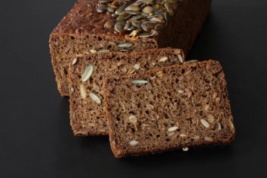 Ev çavdar ekmeği ayçiçeği tohumu ile pişmiş ve siyah arka plan - yakın fotoğraf siyah arka plan üzerine kadar yığılmış dilimleri kesti