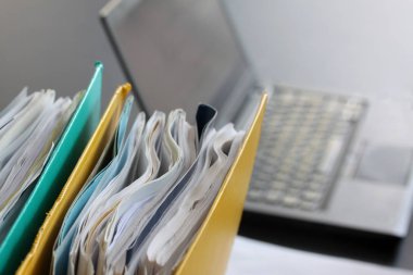Dizüstü bilgisayar, kağıt sayfalarının ve yüzük bağlayıcılar ofis masaları kağıtlara dolu. Seçici odak