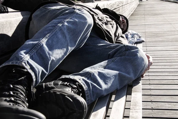 Evsiz adam ya da mülteci ahşap bankta uyuyor 