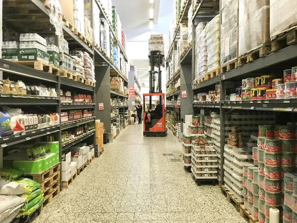 Yerden tavana koridor lar ve raflar sıraları ile büyük depo toptan. Forklift üst raflara kutuları kaldırma. Kopenhag, Danimarka - 19 Nisan 2019.  