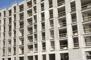Boş alanlar ile çıplak beton duvarların çerçeveleri gösteren çok katlı bir binanın şantiye. Ahşap güvenlik panoları ile korunan konstrüksiyon çalışmaları. Yakın çekim görüntüsü.