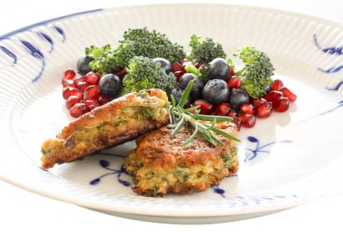 Vejetaryen yemekleri. Kırmızı mercimek, soğan, maydanoz ve yulaf ezmesinden sebze pirzola. Brokoli salatası ile, nar tohumu ve yaban mersini besin çeşitli. Seçici odakla yakın çekim.