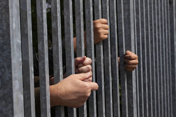 Eller güçlü demir parmaklıkları tutuyor ve uzanıyor. Hapishane ya da göçmen ve mülteci krizi. Dramatik sınır çitveya kavramı 