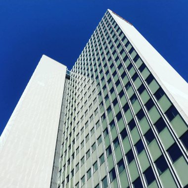 Aşağıdan mavi gökyüzü görünen modern gökdelen binası.