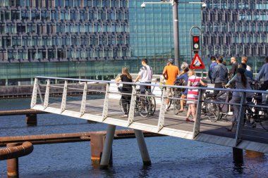 Yayalar ve bisikletli insanlar denizi geçmeden önce yaya köprüsünün kapanmasını bekliyorlar. Arka planda şehir ortamı var. Kopenhag, Danimarka - 29 Ağustos 2017