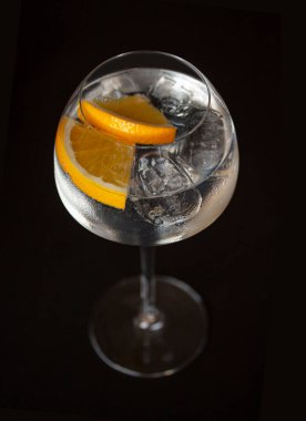 Portakal dilimleri ve buzlu kokteyl. Siyah arka planda zarif bir Hugh kök cam. Yukarıdan seçici bir odak ile çekilmiş .