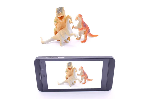 Dinozor oyuncakları beyaz bir grupta akıllı bir telefonla fotoğraflanır.