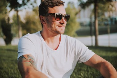 meditative ruh halinde olgun adam çim üzerinde oturan. güneş gözlüğü takmak