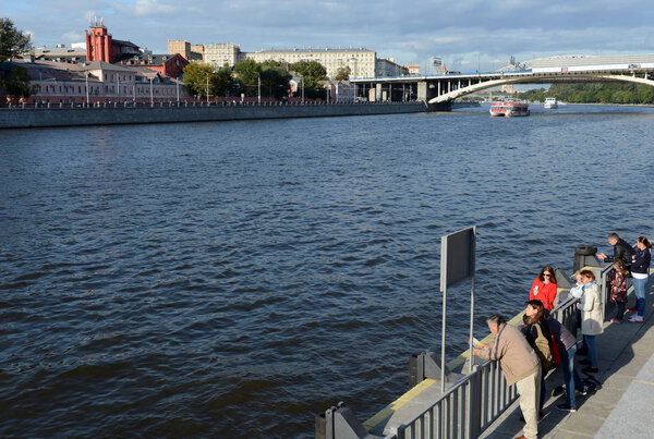  People on the Andreevskaya embankment of the Moskva River are waiting for an excursion boat.
