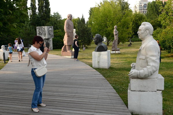  MOSCOW, RUSSIA - JUNE 29, 2018:Unidentified woman photographs the sculpture "Portrait of L. I. Brezhnev" in the Park of arts "Muzeon" in Moscow