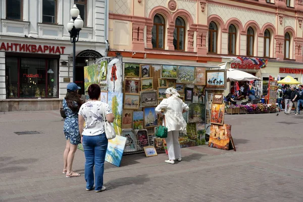 Неизвестные туристы смотрят художественные картины на пешеходной улице Арбат в Москве — стоковое фото
