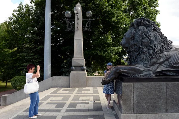 Des touristes inconnus sont photographiés à une sculpture en bronze d'un lion - un fragment du monument à Alexandre II à Moscou — Photo