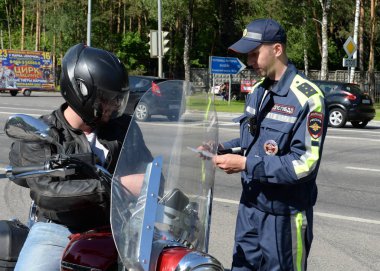  Polis yol devriye servisi müfettişi bir motosiklet sürücüsü belgeleri kontrol eder