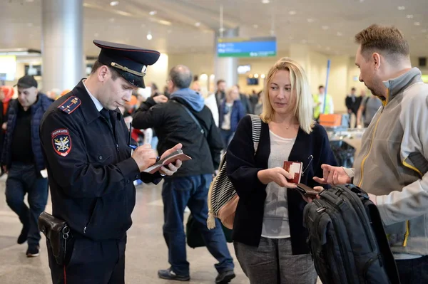 Un oficial de policía revisa los documentos de los pasajeros en una computadora portátil en el Aeropuerto Internacional Domodedovo de Moscú — Foto de Stock