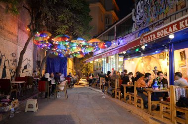 İSTANBUL, TURKEY - 3 Kasım 2019: İnsanlar geceleyin İstanbul 'daki Galata Kulesi' nin yanındaki açık bir kafede dinleniyor