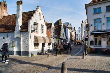 BRUGES, BELGIUM - FEBRUARY 17, 2019: Walplein town square with fabulous houses, medieval architecture. Horse-drawn carriage clipart