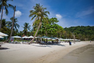 Phu Quoc adası, Vietnam - 31 Mart 2019: Dinlenmek için şezlong lar ve şemsiyelerle donatılmış beyaz kumlu bir plaj. Güney Çin Denizi'nin güzel sahili