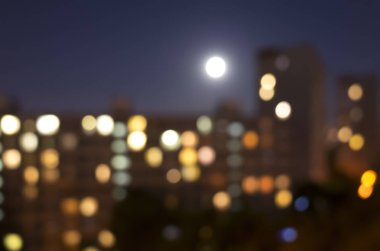 Bulanık gece şehir ışıkları ve dolunay