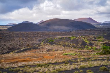 Volkanik dağların ve ayak bağlarının güzel manzarası. Kanarya Adaları özerk topluluğunun bir parçası olarak Las Palmas eyaleti, Lanzarote adası. Dağlar ve bulutlar