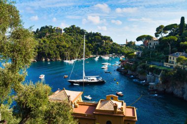Portofino, İtalya - 15 Ağustos 2019: İtalyan Rivierası'nda güzel liman, bir uçurumda evler, tekneler ve su üzerinde bir yat / Avrupa'da popüler bir tatil