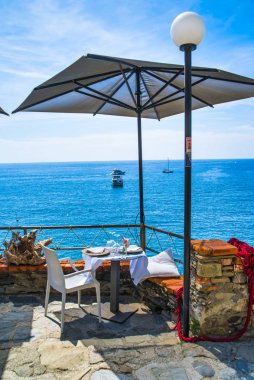 Monterosso al Mare, İtalya - 17 Ağustos 2019: dağda bir kafede şemsiyenin altında masa / deniz manzaralı tekne ve yatlar / Cinque Terre