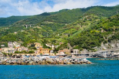 Monterosso al Mare, Cinque Terre, İtalya - 17 Ağustos 2019: İskelede tekneler, tepedeki evler, şehir manzarası / Deniz kıyısındaki şehir plajı