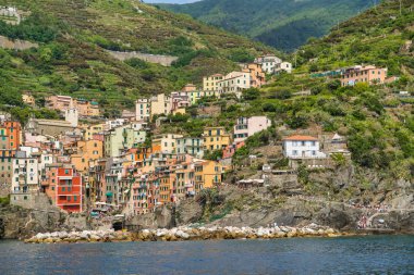 Riomaggiore, Cinque Terre, İtalya - 17 Ağustos 2019: Deniz kıyısındaki köy, kayalık sahilde renkli evler. Avrupa'da popüler bir tatil beldesi