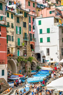 Riomaggiore, Cinque Terre, İtalya - 17 Ağustos 2019: Avrupa'nın popüler tatil beldelerinden biri olan deniz koyu kıyısındaki tekneler. Turistler kayak ve balıkçılık için tekne kiralarlar. Sokakta güzel renkli evler.