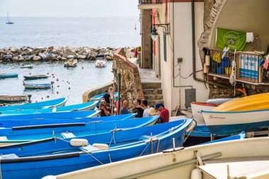 Riomaggiore, Cinque Terre, İtalya - 17 Ağustos 2019: Avrupa'nın popüler tatil beldelerinden biri olan deniz koyu kıyısındaki tekneler. Turistler kayak ve balıkçılık için tekne kiralarlar. Sokakta güzel renkli evler.