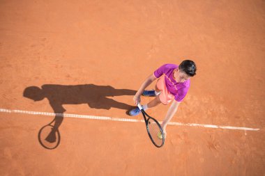 Genç tenisçi topu hizmet için hazırlar